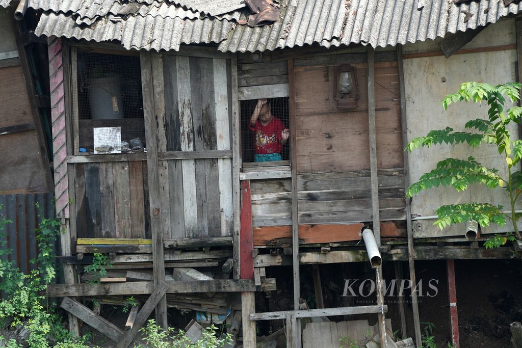 Seorang anak menengok dari balik jendela rumahnya di bantaran Kali Buaran, Cakung, Jakarta Timur, pada 9 Juli 2024. Kemiskinan masih menjadi pekerjaan rumah untuk dihilangkan di Jakarta. 