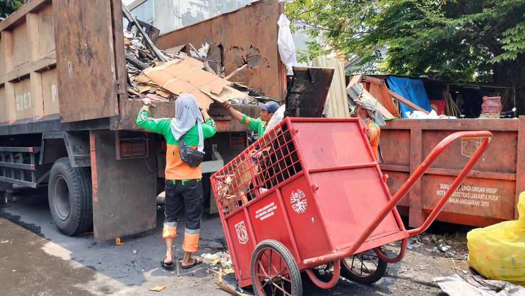 Petugas PPSU tengah memindahkan puing-puing bangunan ke mobil pengangkut sampah di Cikini Kramat, Jakarta Pusat, Selasa (4/10/2022).