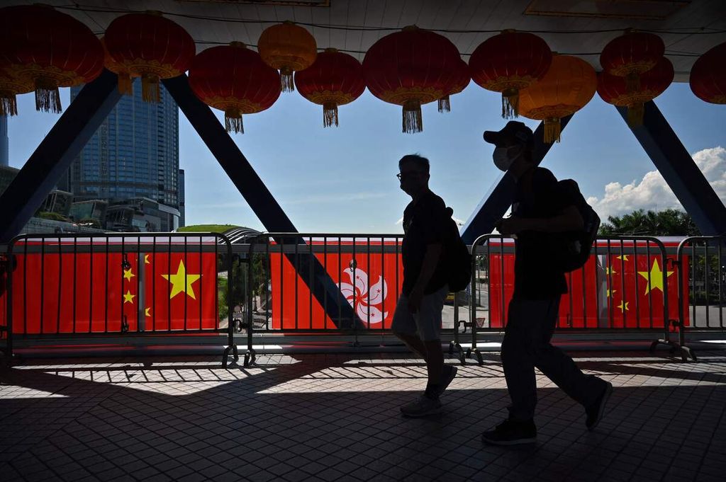 Pejalan kaki berjalan melintas di sebuah koridor yang dihiasi dengan bendera China dan Hong Kong yang dipajang untuk memeringati 25 tahun kembalinya Hong Kong kepada Pemerintah China. Foto diambil di Hong Kong pada Selasa (28/6/2022).