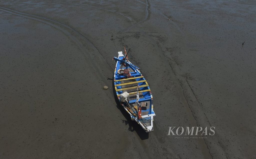 Sebuah perahu kandas saat air laut surut di pesisir Surabaya, Jawa Timur, Selasa (2/1/2024). 