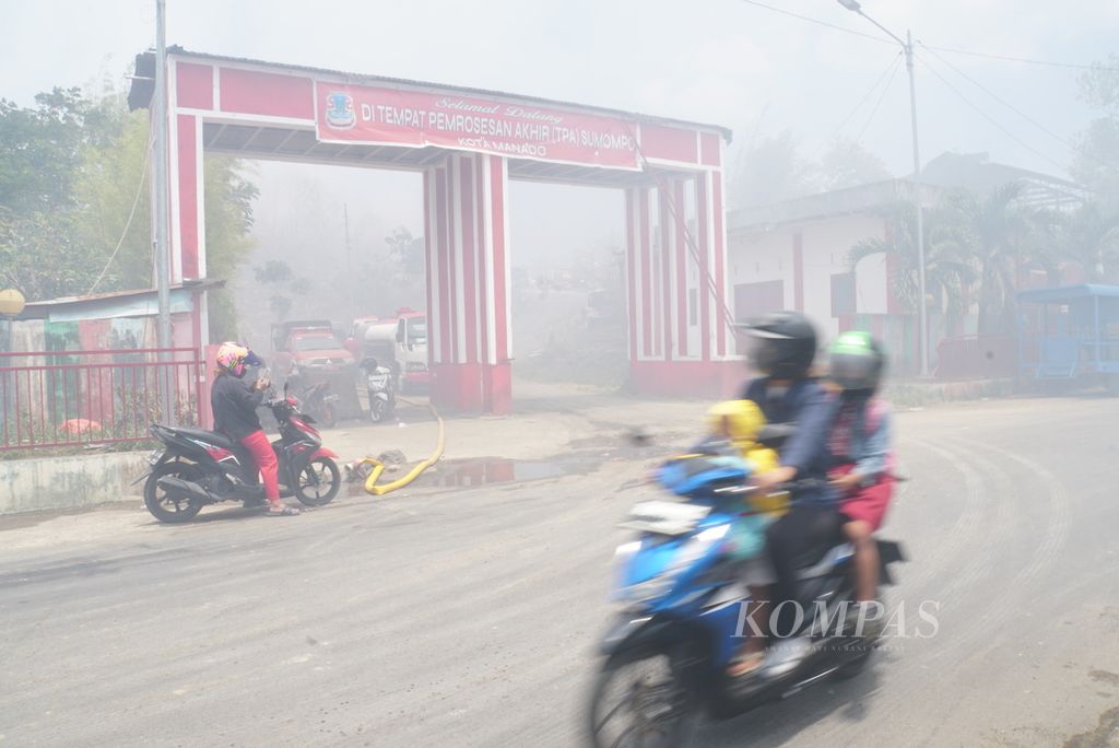 Para pengendara menembus kabut asap yang menyelimuti wilayah sekitar Tempat Pembuangan Akhir (TPA) Sumompo di Manado, Sulawesi Utara, pada Rabu (4/10/2023).