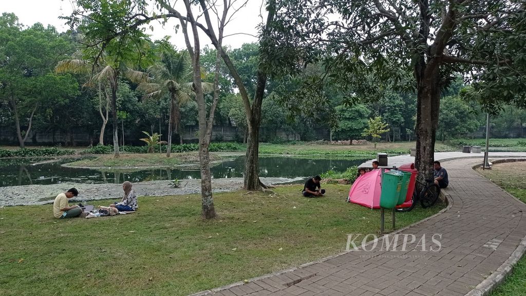 Warga berpiknik di tepi Danau Taman Cempaka, Kelurahan Cilangkap, Kecamatan Cipayung, Jakarta Timur, Minggu (8/10/2023).
