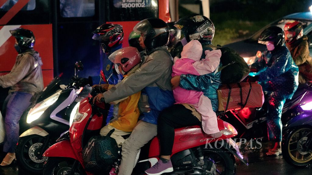 Pemudik sepeda motor membawa anak menembus hujan di perbatasan Jakarta-Bekasi di Jalan Kalimalang, Jakarta Timur, Rabu (27/4/2022). Survei yang dilakukan Badan Litbang Perhubungan pada Maret 2022 menunjukkan tingginya minat publik menggunakan sepeda motor untuk mudik tahun ini. Setidaknya ada 16,9 juta orang yang akan melakukan mudik memakai sepeda motor. Mudik memakai sepeda motor tidak direkomendasikan karena rentan kecelakaan. Namun, sebagian masyarakat akan tetap mudik dengan motor akibat keterbatasan biaya serta transportasi umum. KOMPAS/AGUS SUSANTO (AGS) 27-4-2022