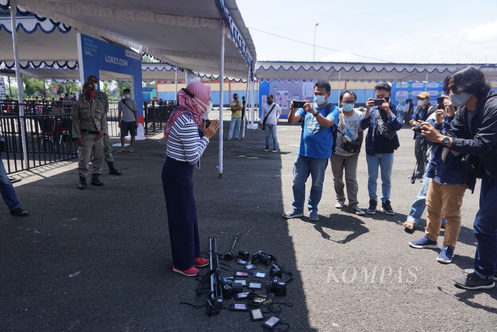 Para wartawan di Kabupaten Banyumas, Jawa Tengah, menggelar aksi protes dengan menghamparkan kartu pers dan alat kerja di luar area vaksinasi yang digelar Kementerian BUMN di GOR Satria Purwokerto, 31 Maret 2021.