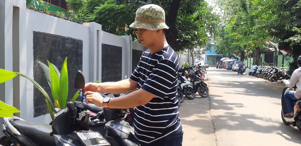  Andrianto (47), petugas parkir di kawasan Palmerah, Jakarta Barat, mengikat motor-motor di kawasan parkirnya dengan tali tambang, Selasa (16/8/2023). Upaya yang merepotkan ini dia lakukan karena maraknya pencurian motor di kawasannya.