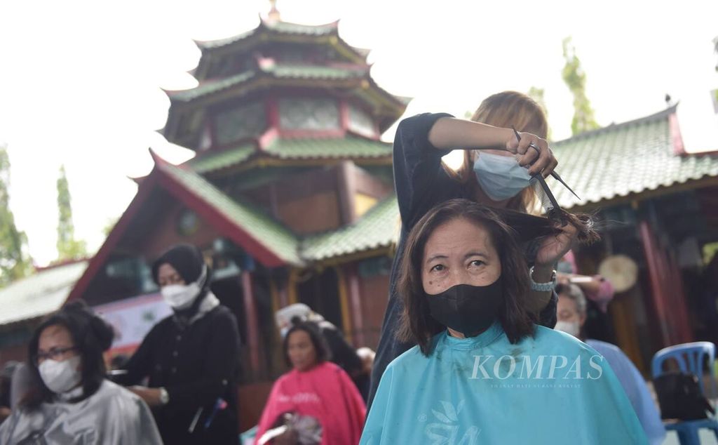 Sukarelawan memotong rambut warga saat kegiatan potong rambut gratis di Halaman Masjid Muhammad Cheng Hoo, Kota Surabaya, Jawa Timur, Senin (18/4/2022). 