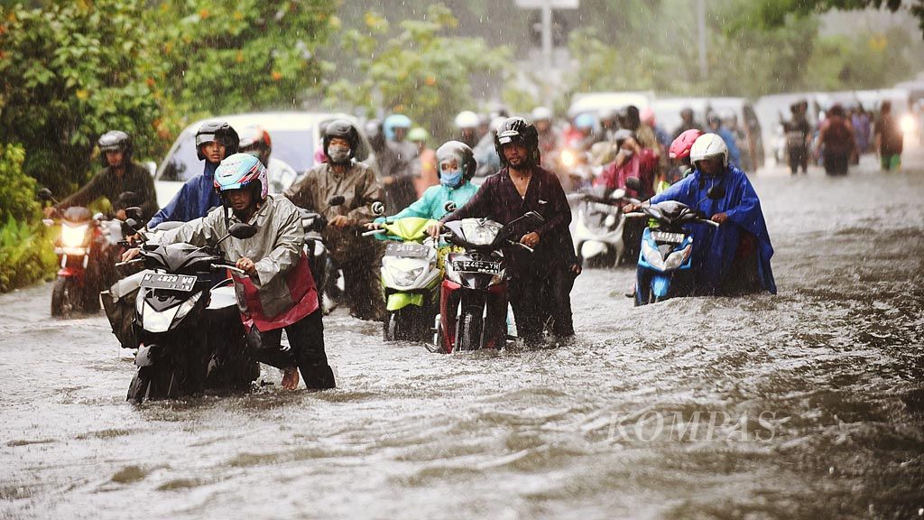 Warga mendorong sepeda motornya yang mogok saat melewati banjir di Jalan Bung Tomo, Kota Surabaya, Jawa Timur, Jumat (24/11). Hujan deras yang mengguyur selama empat jam membuat sejumlah ruas jalan di Kota Surabaya tergenang banjir.