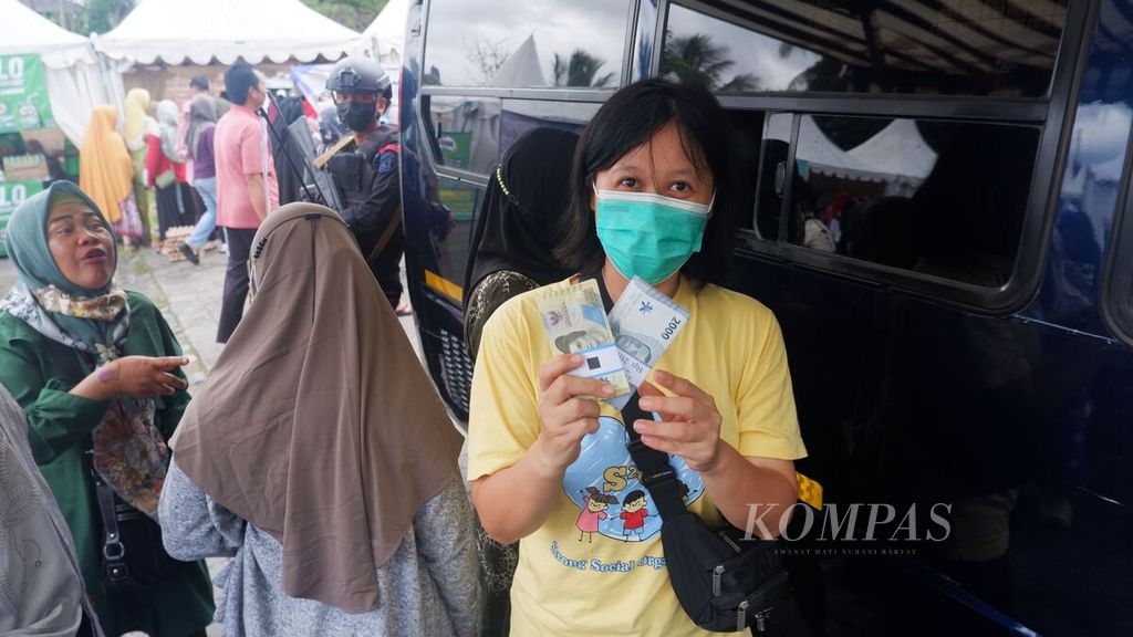 Seorang warga memperlihatkan uang baru yang didapatnya dari penukaran di mobil layanan kas keliling Bank Indonesia di Lapangan Taman Kamboja, Kota Banjarmasin, Kalimantan Selatan, Senin (14/11/2022). 
