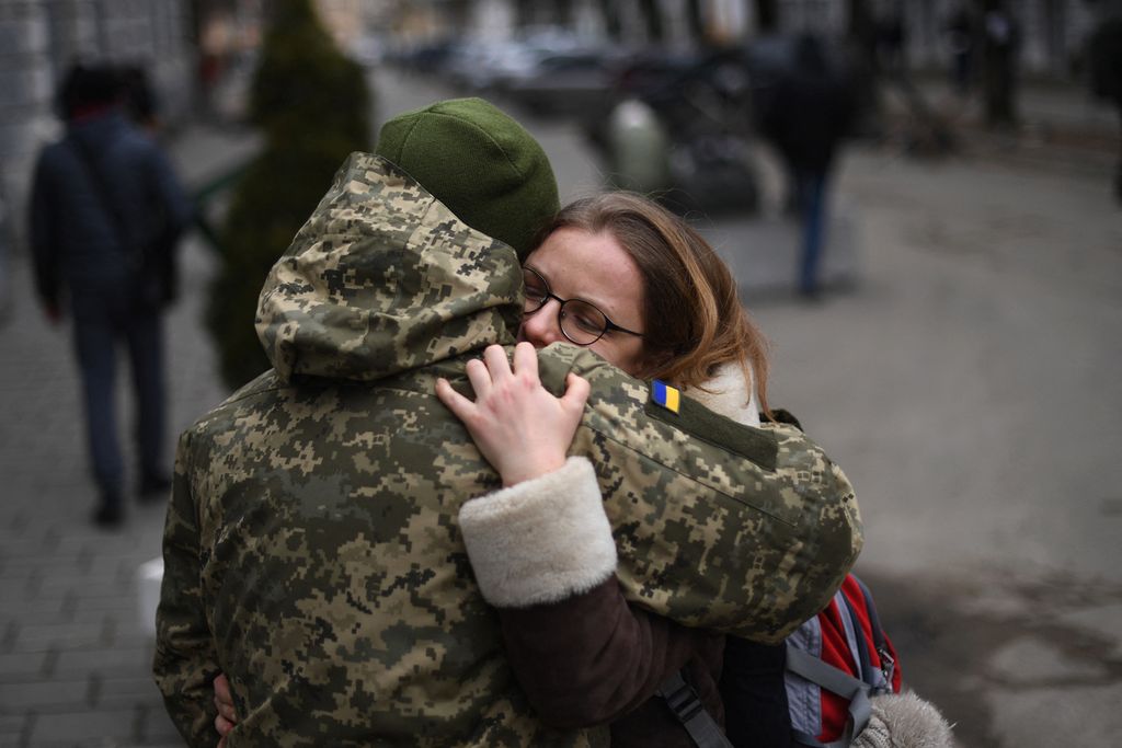 Seorang tentara Ukraina memeluk rekannya di sebelah pangkalan militer tempat penduduk mengantre untuk bergabung dengan tentara di Lviv, Ukraina (2/3/2022). Sebagian besar warga Ukraina menyatakan menentang dan ingin melawan invasi Rusia.