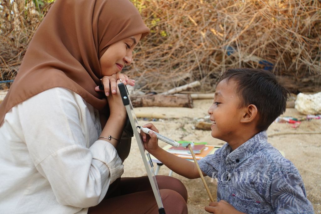 Ezhar (8) bermain tebak kata bersama Nurfadilah Thamrin (21) dalam kelas informal yang diselenggarakan komunitas literasi Aksara Manado, Sabtu (18/11/2023), di Pulau Bunaken, Manado, Sulawesi Utara.