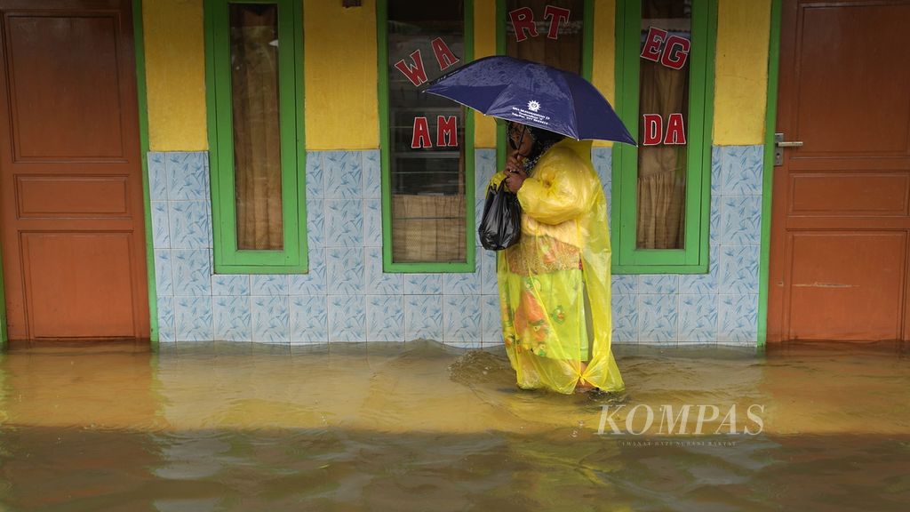 Warga melewati pinggiran warteg menembus air bah yang merendam di Vila Kencana Cikarang di Desa Karangsentosa, Kecamatan Karangbahagia, Kabupaten Bekasi, Jawa Barat, Kamis (2/3/2023). 