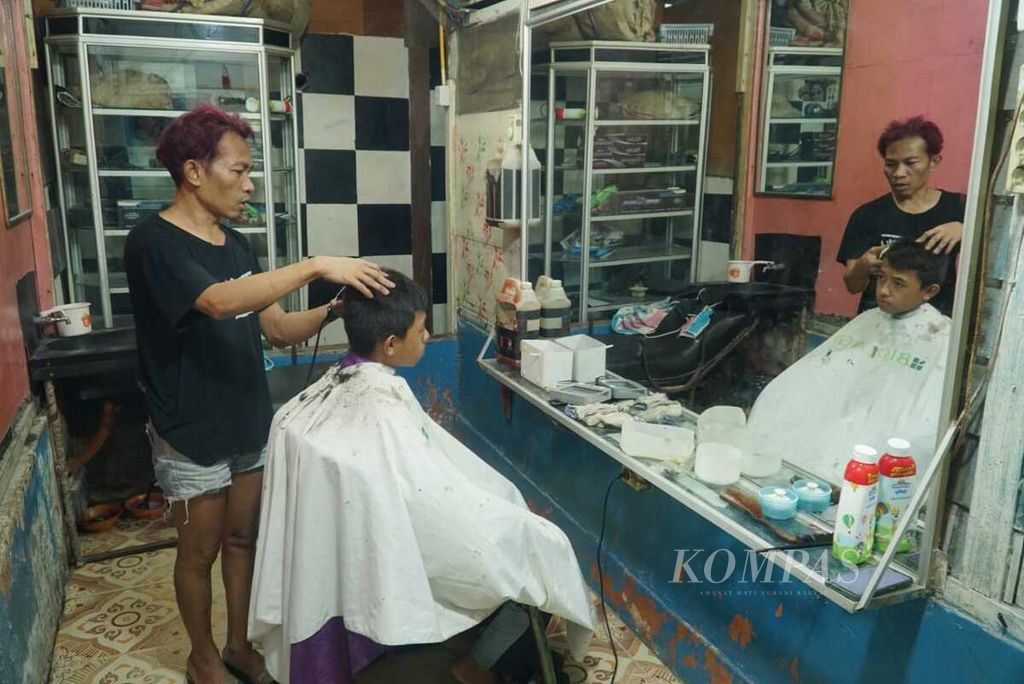 Warga sedang memangkas rambut pelanggan di salon miliknya di Desa Sikakap, Kecamatan Sikakap, Kepulauan Mentawai, Sumatera Barat, Kamis (22/6/2023). Sebagian kegiatan ekonomi masyarakat di Sikakap bergantung pada aliran listrik PLN.