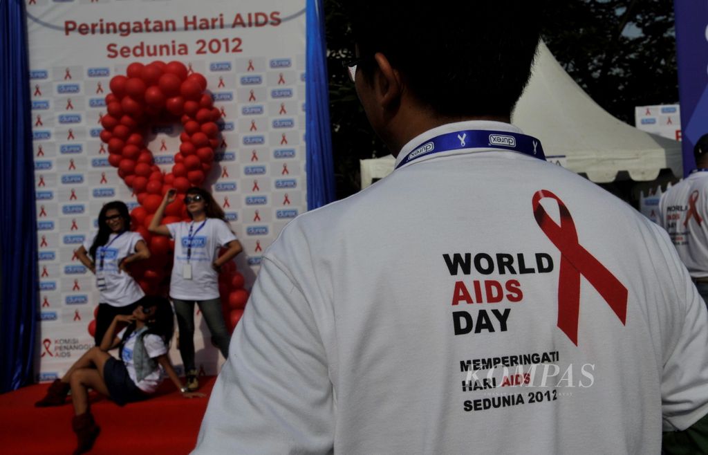 Kampanye Pencegahan AIDS - Warga antre untuk foto gratis dengan latar belakang simbol pita merah sebagai bentuk kepedulian terhadap bahaya HIV/AIDS pada kampanye yang digelar Komisi Penanggulagan AIDS Nasional di Jalan Sudirman, Jakarta, Minggu (2/12/12). Dari tiap warga yang berfoto akan disumbangkan donasi  Rp 10.000 dari sponsor untuk kagiatan kampanye penanggulangan HIV/AIDS di Indonesia.