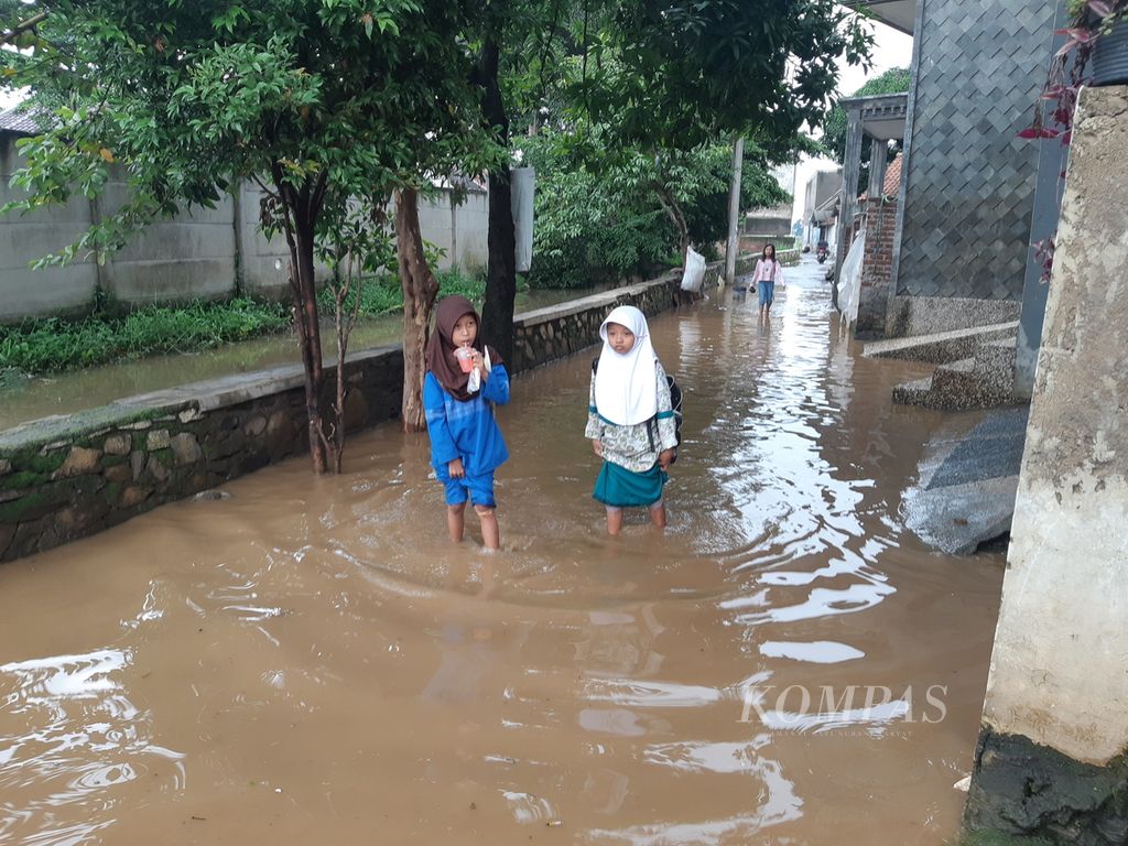 Tampak dua pelajar melewati genangan air di salah satu kompleks perumahan, Kampung Tegalluar, Kecamatan Bojongsoang, Kabupaten Bandung, Jawa Barat, Rabu (10/1/2024). Banjir terjadi di lima kecamatan. Kabupaten Bandung, selama tiga hari terakhir.