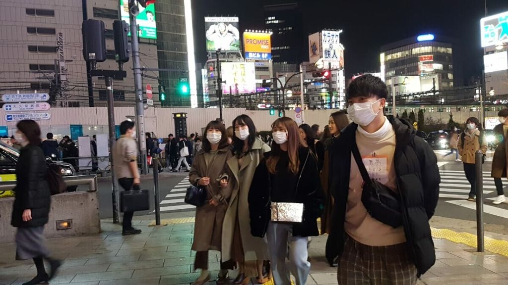 Warga Tokyo memakai masker di kawasan Shinjuku, Tokyo pada Sabtu (29/2/2020) malam. Di kawasan itu berkembang kamar kos ukuran 9 meter persegi yang diminati para pekerja muda dan lajang. Biasanya sewanya Rp 8 juta per bulan