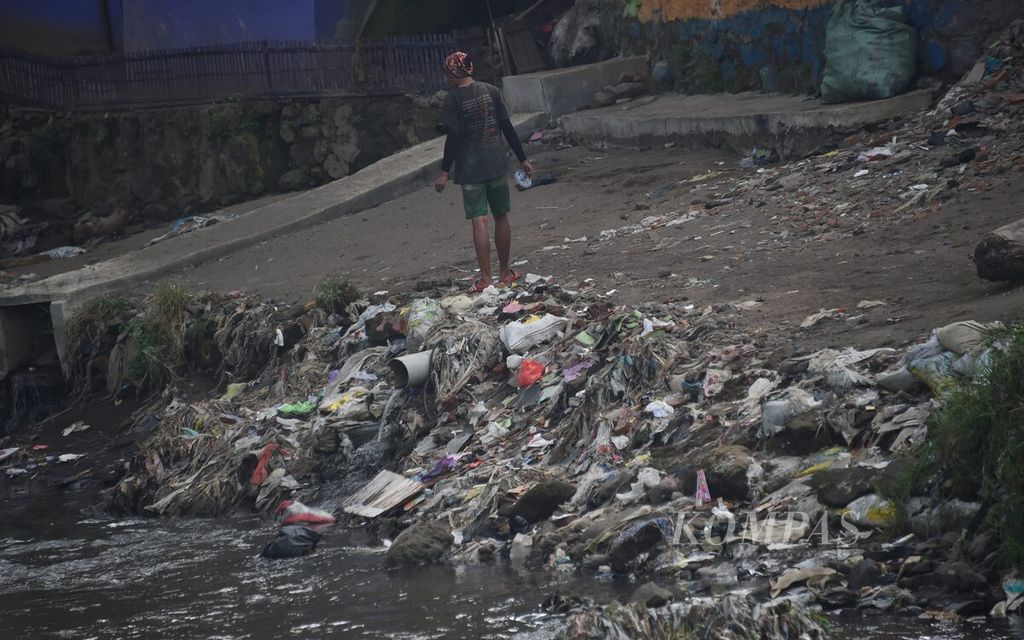 Warga berada di dekat tumpukan sampah di pinggir Daerah Aliran Sungai Brantas di Kota Malang, Jawa Timur, Minggu (23/5/2021). Kawasan hulu Sungai Brantas tersebut dimanfaatkan warga sebagai sumber pengairan, juga aktivitas menambang pasir dan batu. 