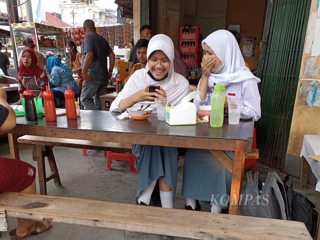 Siswi SMA beraktivitas di sebuah rumah makan di Jalan Iskandar Muda, Medan, Sumatera Utara, Selasa (2/8/2022). Di tengah peningkatan kasus baru Covid-19, Kota Medan meningkatkan protokol kesehatan dengan kriteria PPKM level I. 