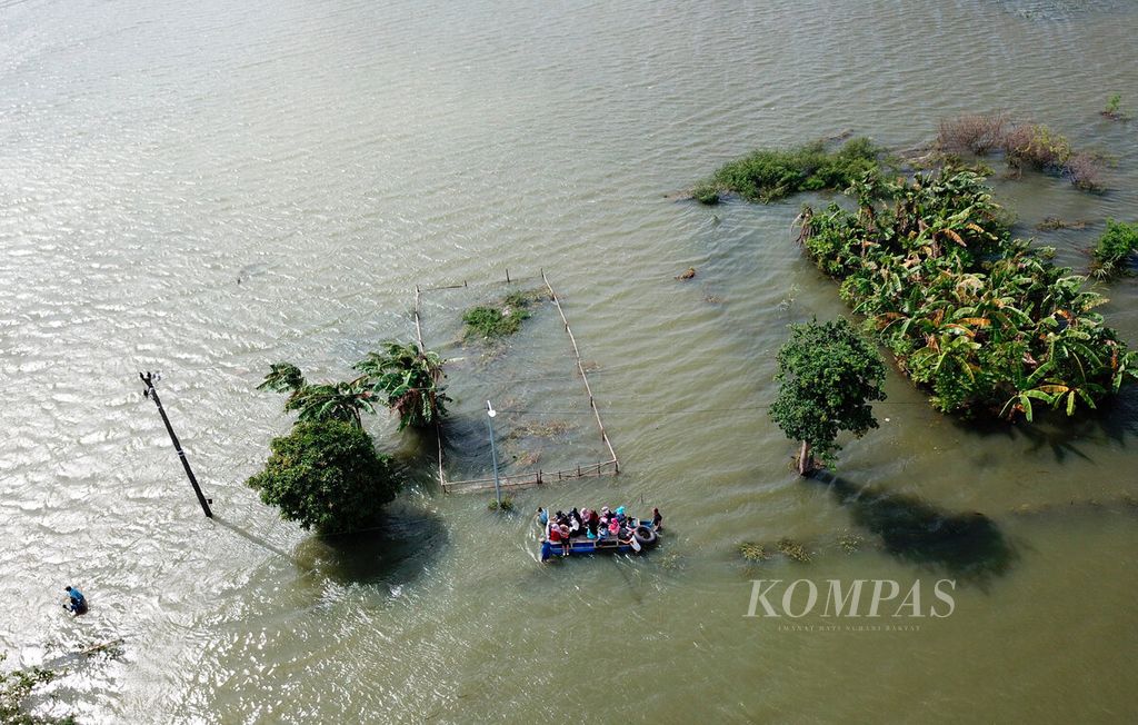 Warga menggunakan perahu melintasi genangan banjir yang mengisolasi permukiman mereka di Desa Kedungdowo, Kecamatan Kaliwungu, Kabupaten Kudus, Jawa Tengah, Rabu (4/1/2023). 