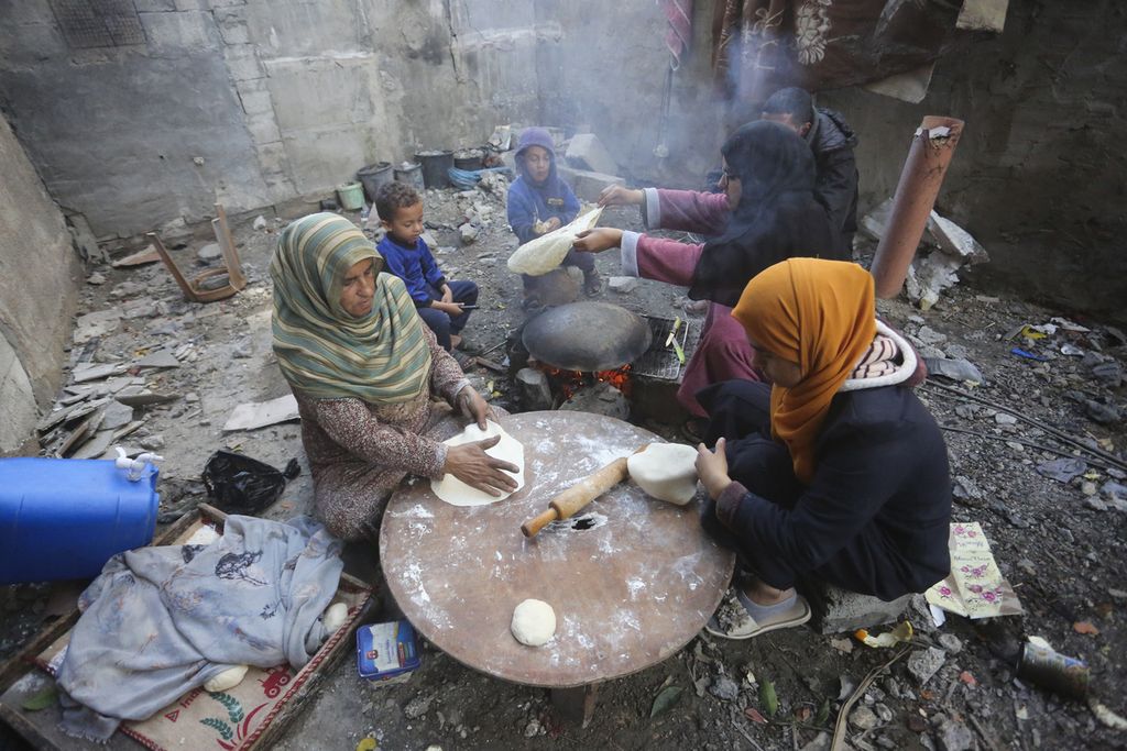 Beberapa perempuan warga Palestina menggunakan peralatan seadanya membuat roti di tengah-tengah reruntuhan bangunan rumah mereka di Kuza, Jalur Gaza, Rabu (29/11/2023). 