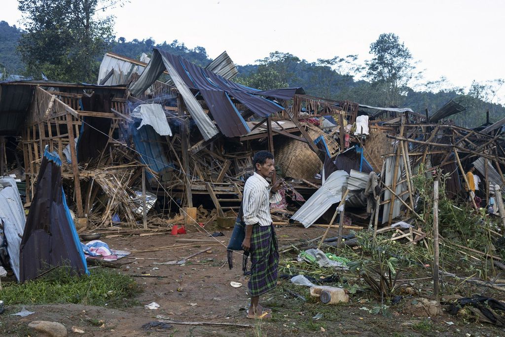Seorang pria berdiri di dekat rumah yang hancur akibat serangan udara dan artileri di kamp Mung Lai Hkyet, Laiza, Selasa (10/10/2023).