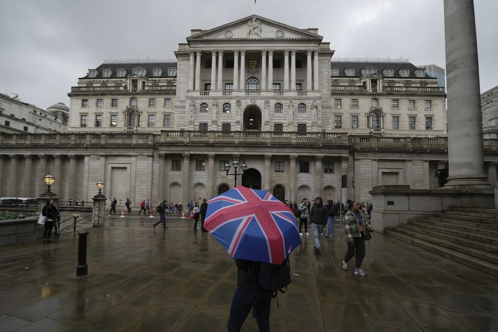 Seorang perempuan dengan payung berdiri di depan Bank of England di kawasan keuangan di London, Kamis (3/11/2022). Bank of England mengumumkan kenaikan suku bunga acuan tertinggi dalam tiga dekade terakhir guna mengatasi inflasi yang meroket.