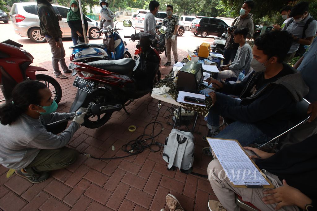 Petugas memasukkan alat penguji emisi ke knalpot sepeda motor saat berlangsung uji emisi gratis di halaman GOR Senam DKI Raden Inten, Jakarta Timur, Selasa (29/3/2022). 