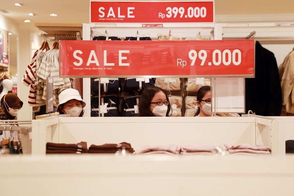 Salah satu warga melihat harga pada celana yang dijual di salah satu toko pusat perbelanjaan di kawasan Jakarta Selatan, Minggu (18/12/2022). Menjelang Natal dan Tahun Baru pusat perbelanjaan mulai ramai dikunjungi. 