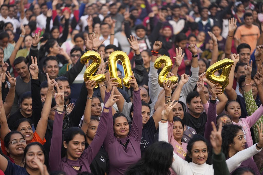 Masyarakat Ahmedabad, India, memegang angka 2024 dan bersorak ketika merayakan malam Tahun Baru 2024, Minggu (31/12/2023).