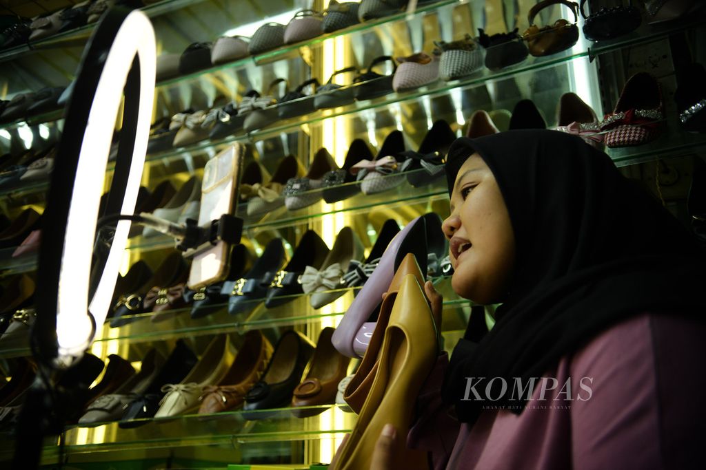 Pedagang menawarkan sepatu kepada para pengguna media sosial Tiktok saat siaran langsung di kios Blok A Pasar Tanah Abang, Jakarta, Selasa (13/6/2023). Penjualan secara daring menjadi salah satu strategi pedagang untuk menjangkau konsumen yang lebih luas. 