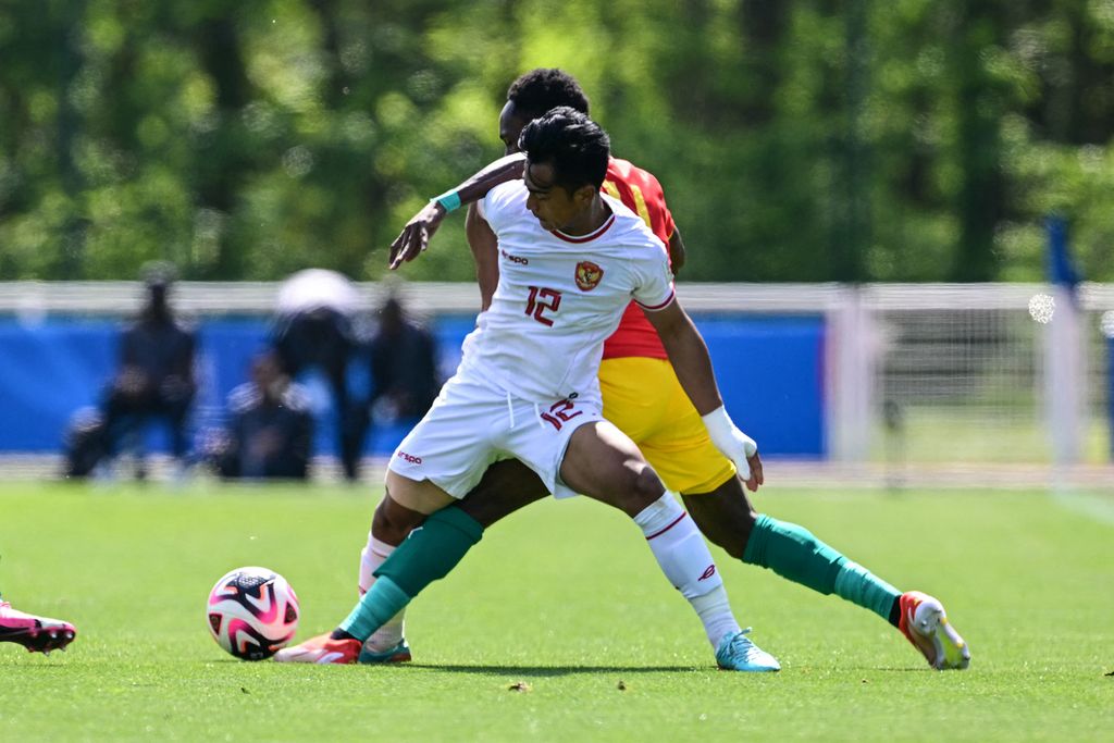 Indonesia U-23 defender, Pratama Arhan Rifai, fights for the ball with Guinea striker, Ousmane Camara, in the 2024 Paris Olympics playoff match in Clairefontaine, south of Paris, France, Thursday (9/5/2024). Indonesia must face Guinea to get a place at the 2024 Paris Olympics after two opportunities to qualify directly through the U-23 Asian Cup which took place in Qatar failed.