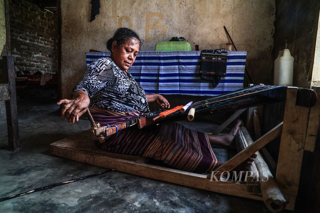 Katarina Kremo Tapoona (57) menenun kain di rumahnya di Desa Lamalera A, Kabupaten Lembata, Nusa Tenggara Timur, Kamis (23/11/2023). Tradisi berburu paus di Lamalera salah satunya mewujud dalam obyek kebudayaan pengetahuan tradisional berupa menenun yang disebut tani tenane. 