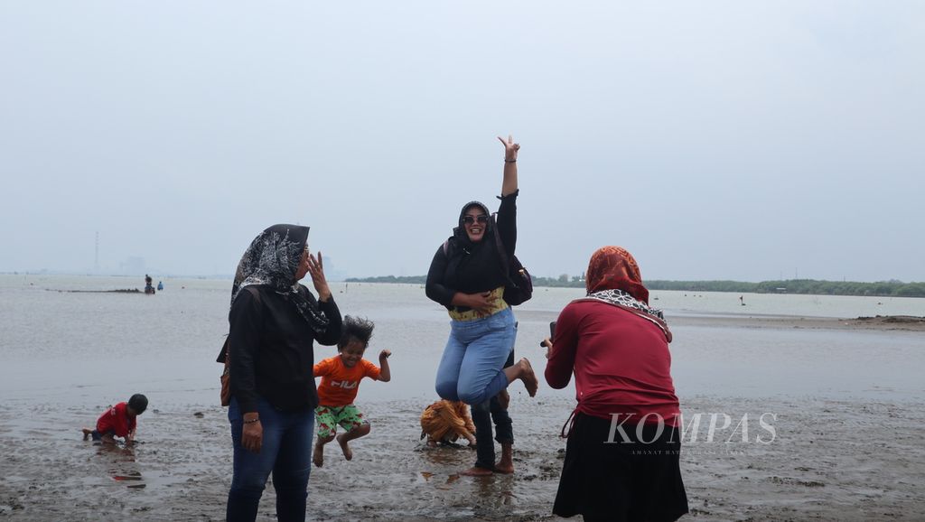 Wisatawan berfoto dengan latar belakang pantai di Wisata Bahari Kejawanan di Kota Cirebon, Jawa Barat, Sabtu (4/2/2023). Pantai Kejawanan menjadi salah satu destinasi wisata bahari di Cirebon. Saat akhir pekan, ribuan orang berwisata ke tempat tersebut.