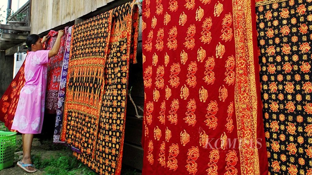 Menjelang  Idul Fitri, sejumlah perajin  memproduksi batik untuk pakaian gamis. Hal itu untuk menyiasati pemasaran agar tetap stabil di masa Lebaran. Siti Hajir, perajin di sentra batik kawasan Seberang, Kota Jambi, menjemur hasil pewarnaan batik, Jumat (16/6).