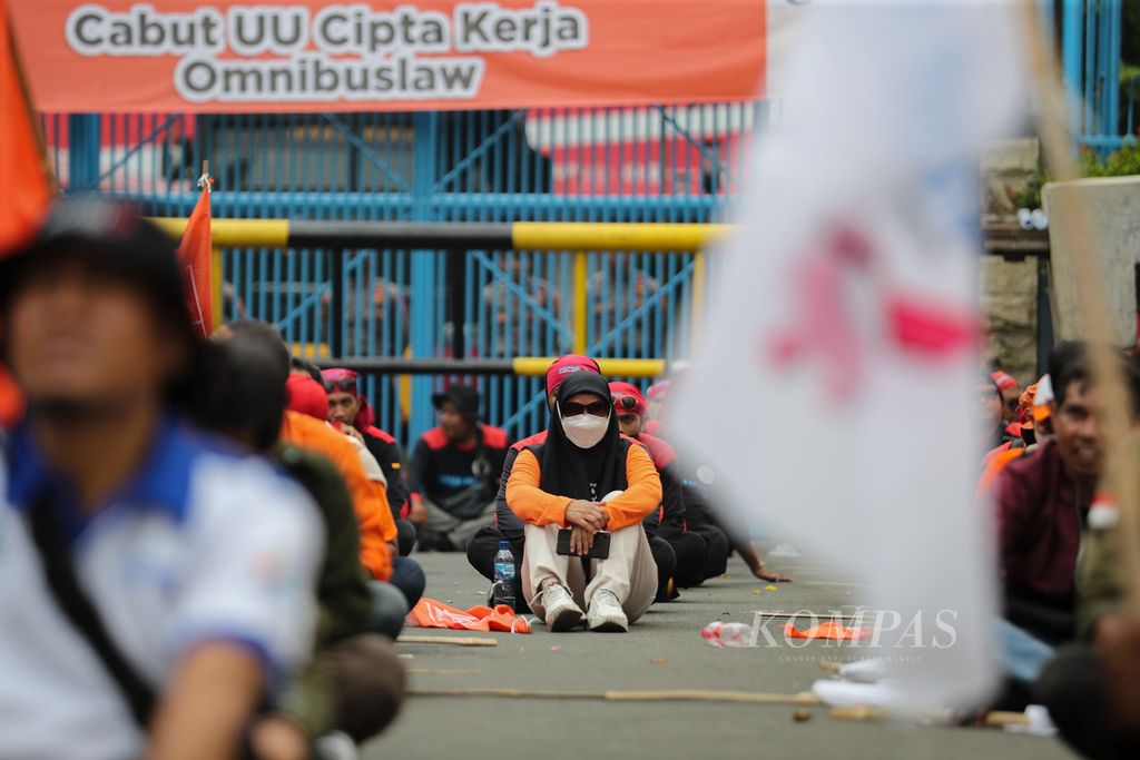 Peserta aksi duduk di tengah aksi di depan Kementerian Ketenagakerjaan, Jakarta, Kamis (21/9/2023). Mereka meminta pemerintah untuk menaikkan upah minimum sebesar 15 persen pada 2024. 