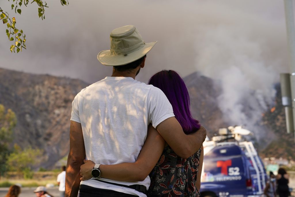 Sepasang suami istri menyaksikan api yang membakar hutan di Azusa, California, Amerika Serikat, Kamis (13/8/2020). 