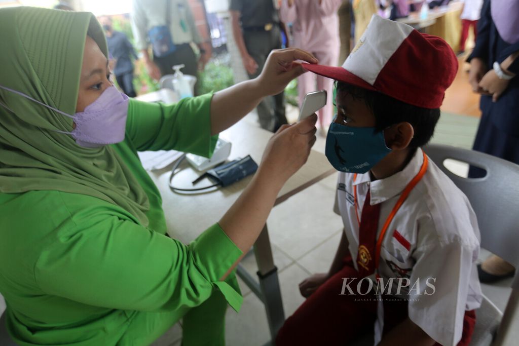 Tenaga kesehatan melakukan pemeriksaan kesehatan kepada siswa sebelum menerima suntikan vaksin Covid-19 di SDN 02 Pondok Bambu, Jakarta Timur, Selasa (14/12/2021).
