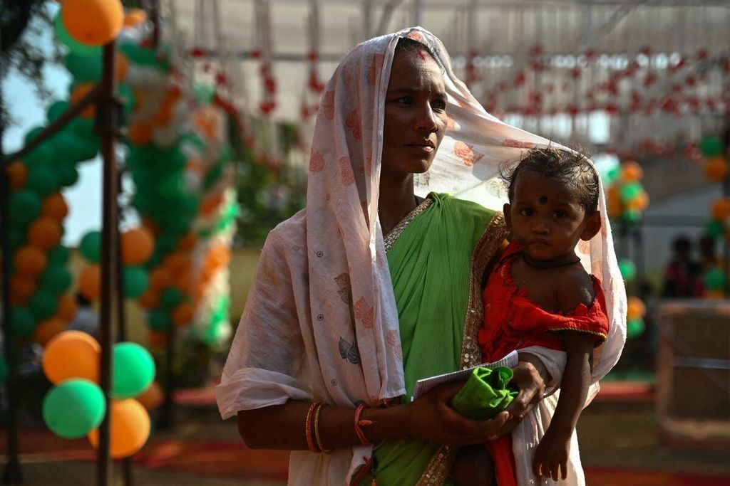 A voter is carrying their child while waiting for their turn to cast their vote in the Indian elections at a polling station in Dugeli Village, Chhattisgarh State, India, on April 19, 2024.