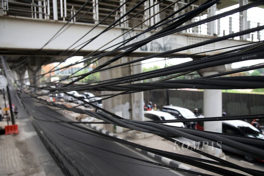 Jaringan utilitas di Jalan Ciledug Raya, Jakarta Selatan, Rabu (2/8/2023). Penataan jaringan utilitas menjadi masalah bagi daerah perkotaan. Sebagian besar jaringan utilitas ini masih terpasang di jaringan atas yang sering terlihat semrawut, tumpang tindih, hingga menjuntai yang bisa membahayakan pengguna jalan. 