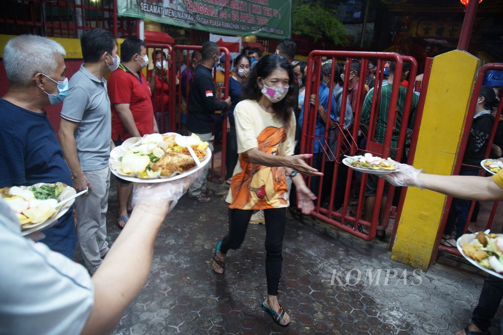 Pengurus Wihara Dharma Bhakti-Klenteng Kim Tek Ie membagikan makanan kepada warga Petak Sembilan, Glodok, Jakarta Barat, Selasa (19/4/2022), saat buka puasa bersama.