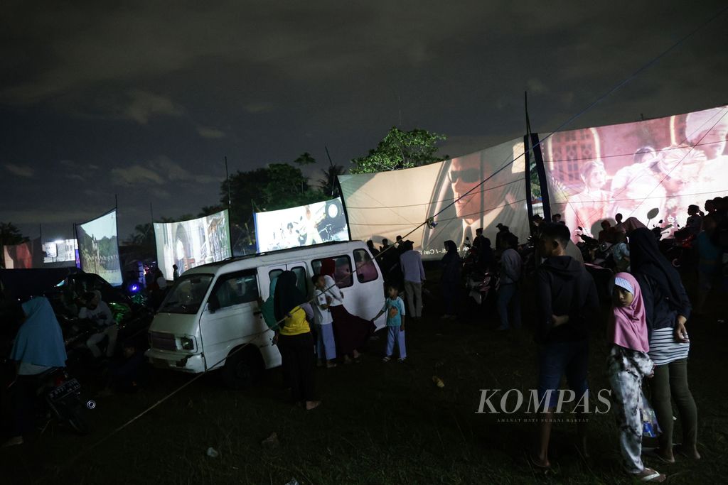 Antusiasme warga yang menyaksikan film dalam festival layar tancap di Lapangan Babakan, Kecamatan Setu, Tangerang Selatan, Banten, Rabu (18/1/2023) malam. Sebanyak 21 layar tancap memutar film berbagai genre secara bersamaan.