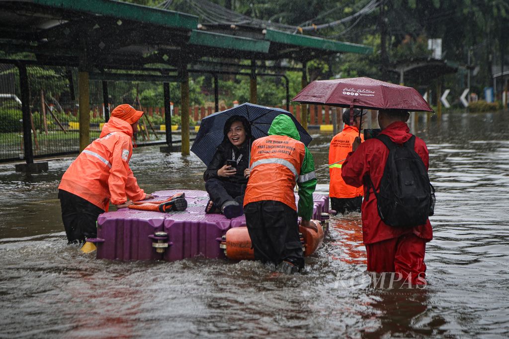 Petugas dari Dinas Lingkungan Hidup DKI Jakarta membantu warga yang menerobos genangan air di kawasan Cempaka Putih, Jakarta Pusat, Kamis (29/2/2024).