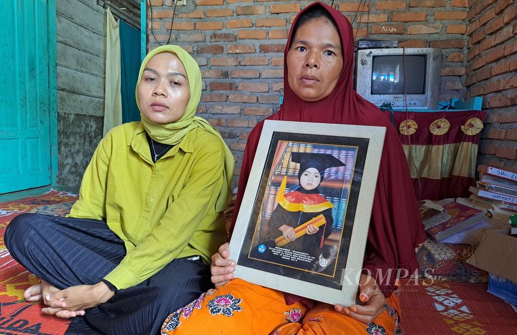 Murniati (48, right), the mother, shows a photo of her late daughter, Aldelia Rahma, during her kindergarten graduation at her home in Nagari III Koto Aur Malintang, IV Koto Aur Malintang District, Padang Pariaman Regency, West Sumatra, on Friday (24/5/2024).