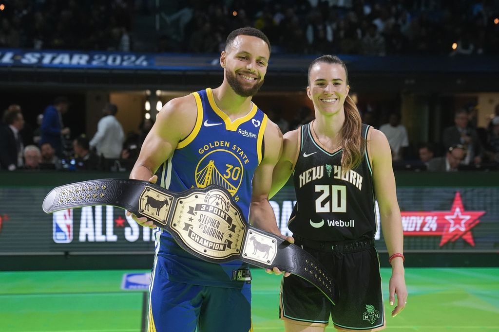 Stephen Curry memegang sabuk juara kontes tiga angka seusai melawan Sabrina Ionescu pada acara NBA All-Star, Minggu (18/2/2024) dini hari WIB. 