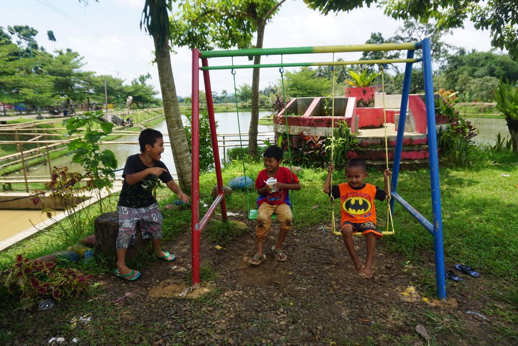 Andra (8), Fino (6), dan Abe (5) bermain ayunan di sekitar Embung Rawa Bener, Desa Piasa Kulon, Kecamatan Somagede, Kabupaten Banyumas, Jawa Tengah, Selasa (8/11/2022). Selain ayunan, ada juga wahana memanjat jaring hingga naik becak air berbentuk bebek atau angsa warna-warni.