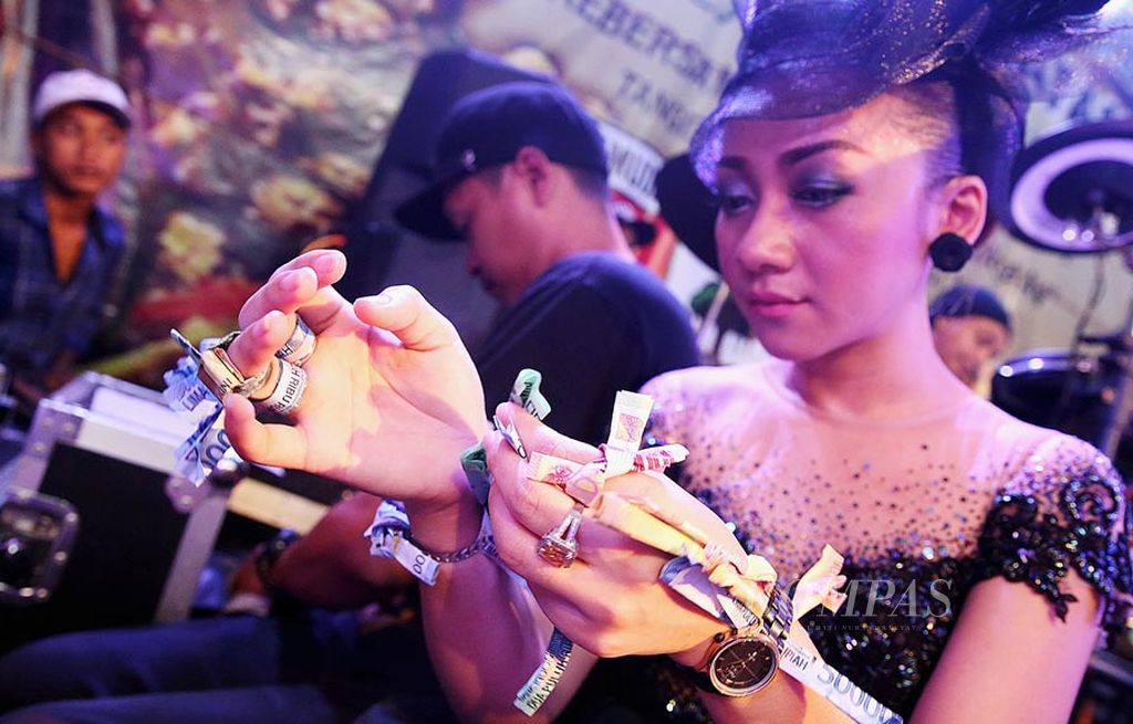 Penyanyi grup dangdut Familys, Elys Muenchen, menghitung uang saweran dari penonton setelah bernyanyi di sebuah pentas di kawasan Ciputat, Tangerang Selatan, Jumat (7/7), malam.
