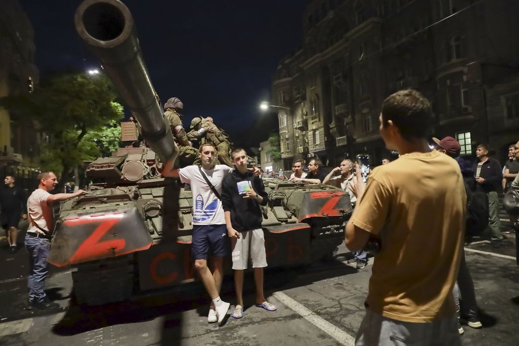 Anggota kelompok tentara bayaran Wagner duduk di ats sebuah tank saat warga sipil berfoto sebelum mereka meninggalkan area markas pusat Distrik Militer Selatan di Rostov-on-Don, Rusia, 24 Juni 2023. 