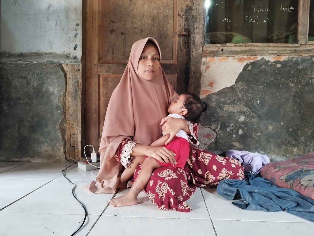 Nurlaelah (39) hugs Bilqis, her 10th child, on the terrace of her house in Cibarusahjaya Village, Cibarusah District, Bekasi Regency, West Java, Friday (7/4/2023).