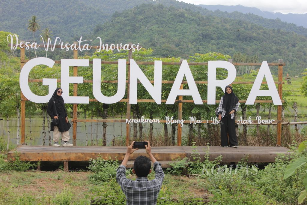 Tiga wisatawan lokal berfoto di hamparan sawah di Desa Geunteut, Kecamatan Lhoong, Kabupaten Aceh Besar, Aceh, Sabtu, 4 Juni 2022. Desa Geunteut dikenal dengan durian dan nilam. Kini kedua komoditas itu dikemas sebagai paket wisata.