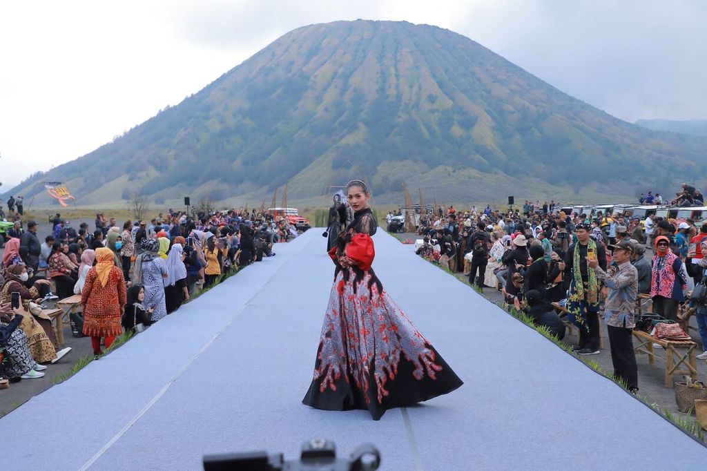 Seorang model memperagakan busana karya desainer di kawasan Taman Nasional Bromo Tengger-Semeru, Sabtu (3/12/2022). Sejumlah busana berbahan kain wastra Jatim dan Nusantara ditampilkan dalam gelaran East Java Fashion Harmony. Selain mengenalkan keragaman kain Nusantara, acara itu juga mempromosikan wisata. 