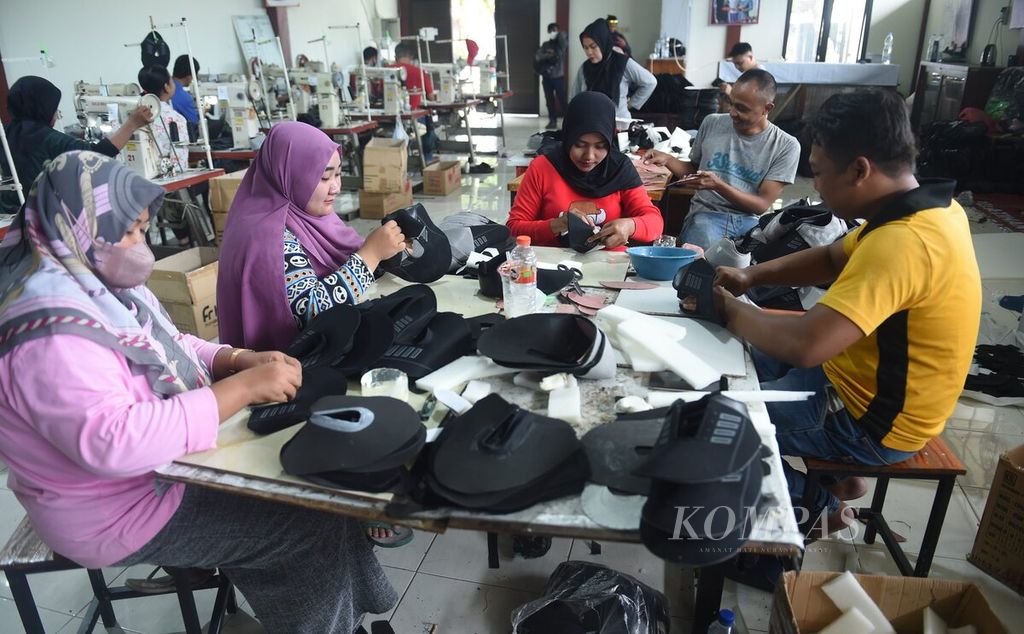 Perajin memeriksa sepatu bagian atas yang akan dijahit di <i>workshop</i> IKM Alas Kaki, Kota Mojoketo, Jawa Timur, Selasa (11/10/2022). IKM Alas Kaki juga rutin menyelenggarakan pelatihan menjahit alas kaki bagi warga setempat dan pekerja yang mengalami pemutusan hubungan kerja.